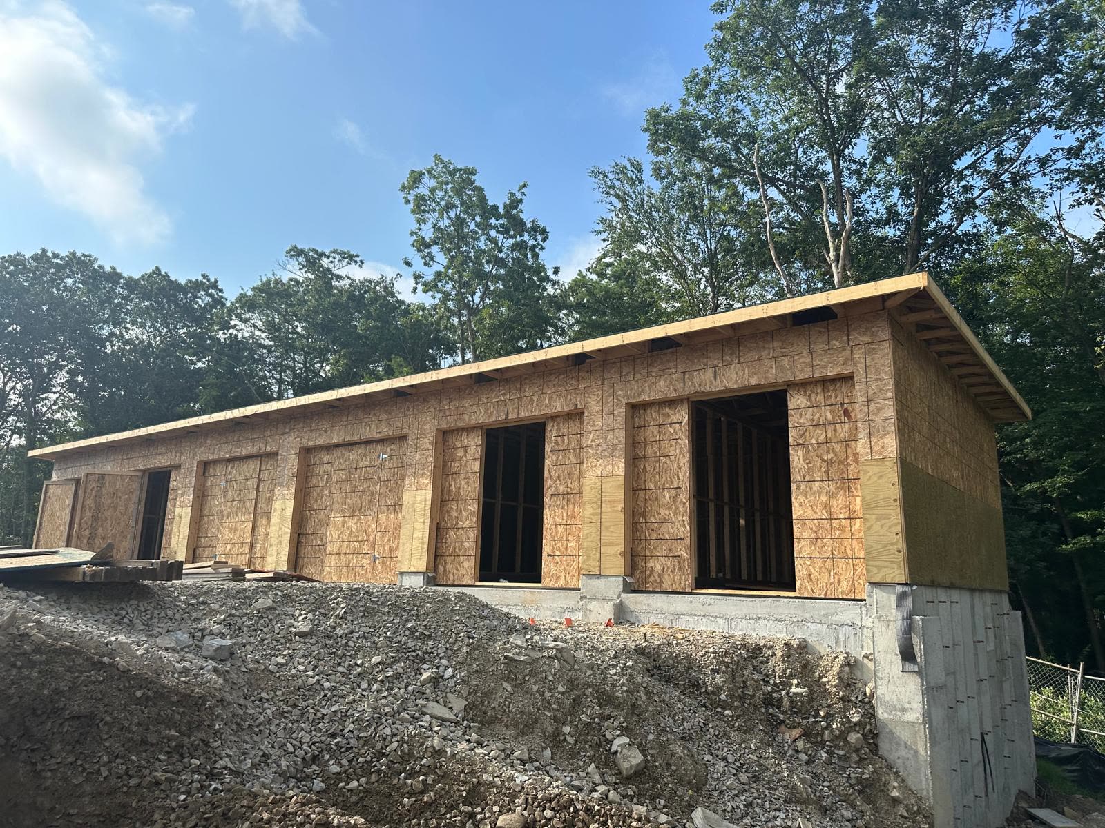 Wood-framed garage building under construction with open stud walls and framed door openings
