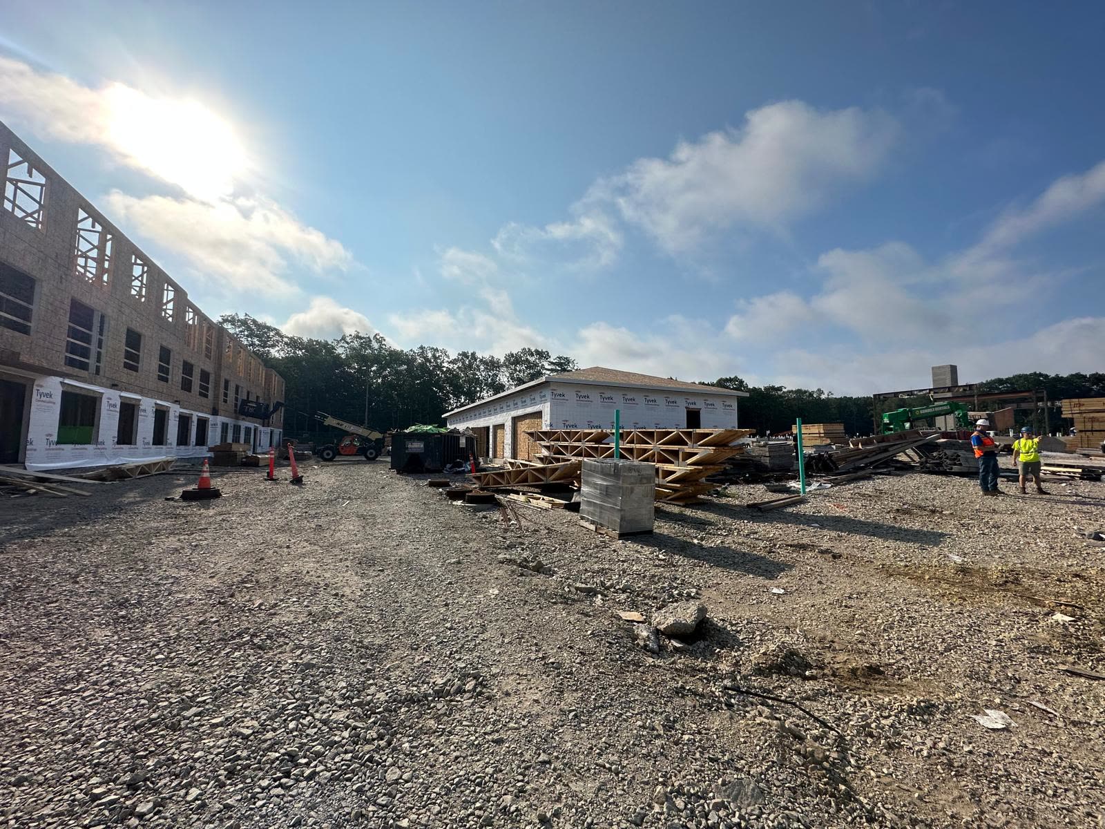 Floor trusses stacked at a jobsite in front of a wrapped multifamily building